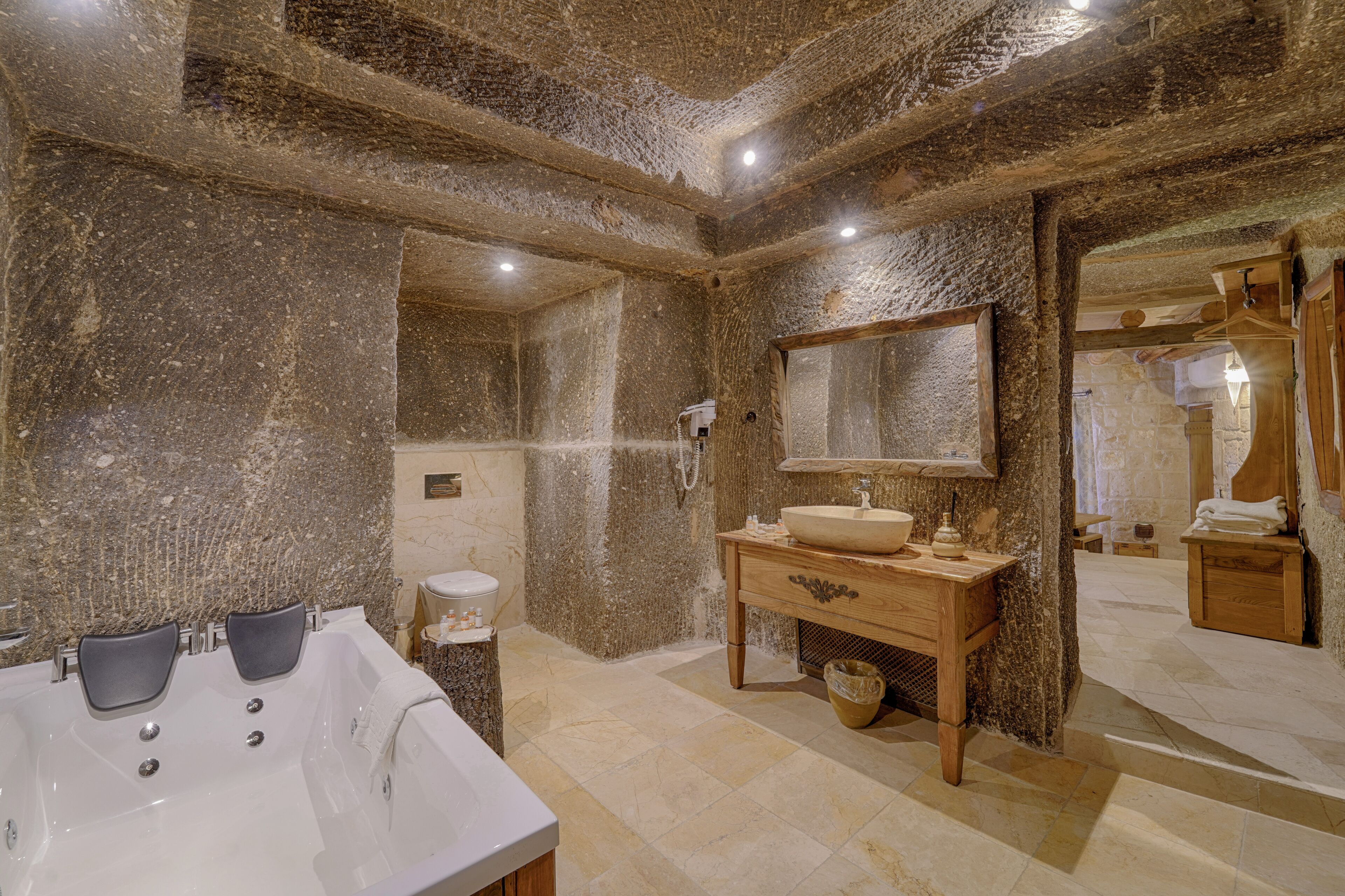 A bathroom with a large bathtub, a wooden vanity, a mirror, and a shower area.