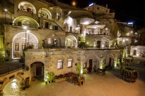 A historic building with multiple balconies, stone arches, and outdoor seating areas with potted plants. - Hera Cave Suites (Nevsehir)
