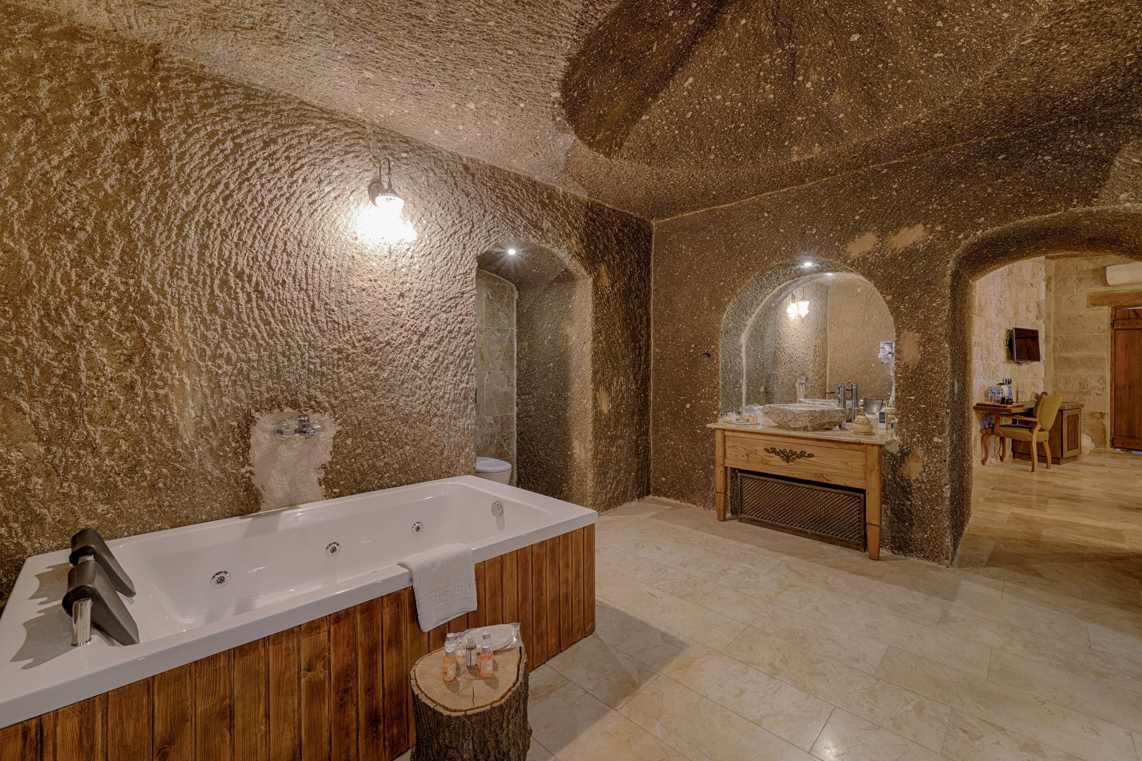 Un baño moderno con una bañera grande, tocador de madera y una pared de piedra rústica.