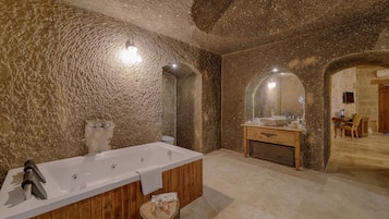 Un baño moderno con una bañera grande, tocador de madera y una pared de piedra rústica.