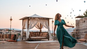 Una donna con un abito verde su un pontile di legno, con un tendale e vista sulla città sullo sfondo.