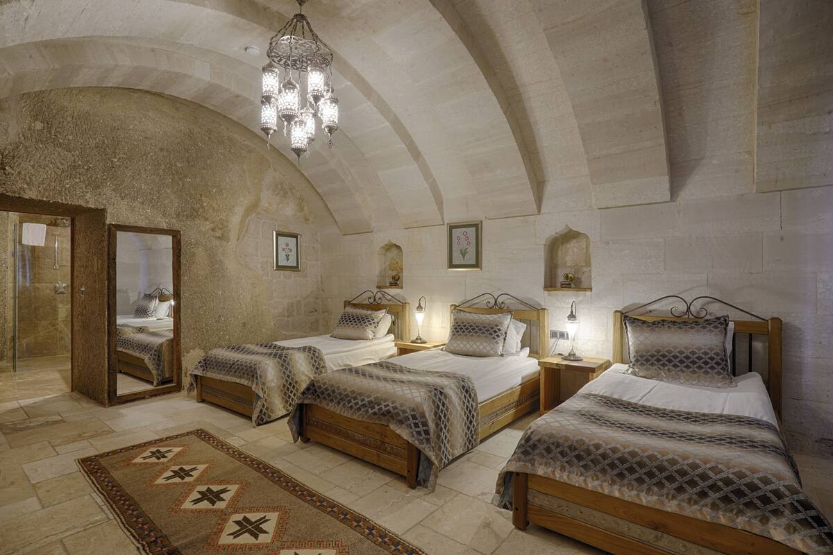A bedroom with three wooden beds, a chandelier, and a large mirror.