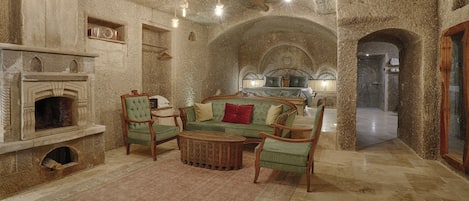 A cozy living room with a fireplace, green upholstered furniture, and a patterned rug.