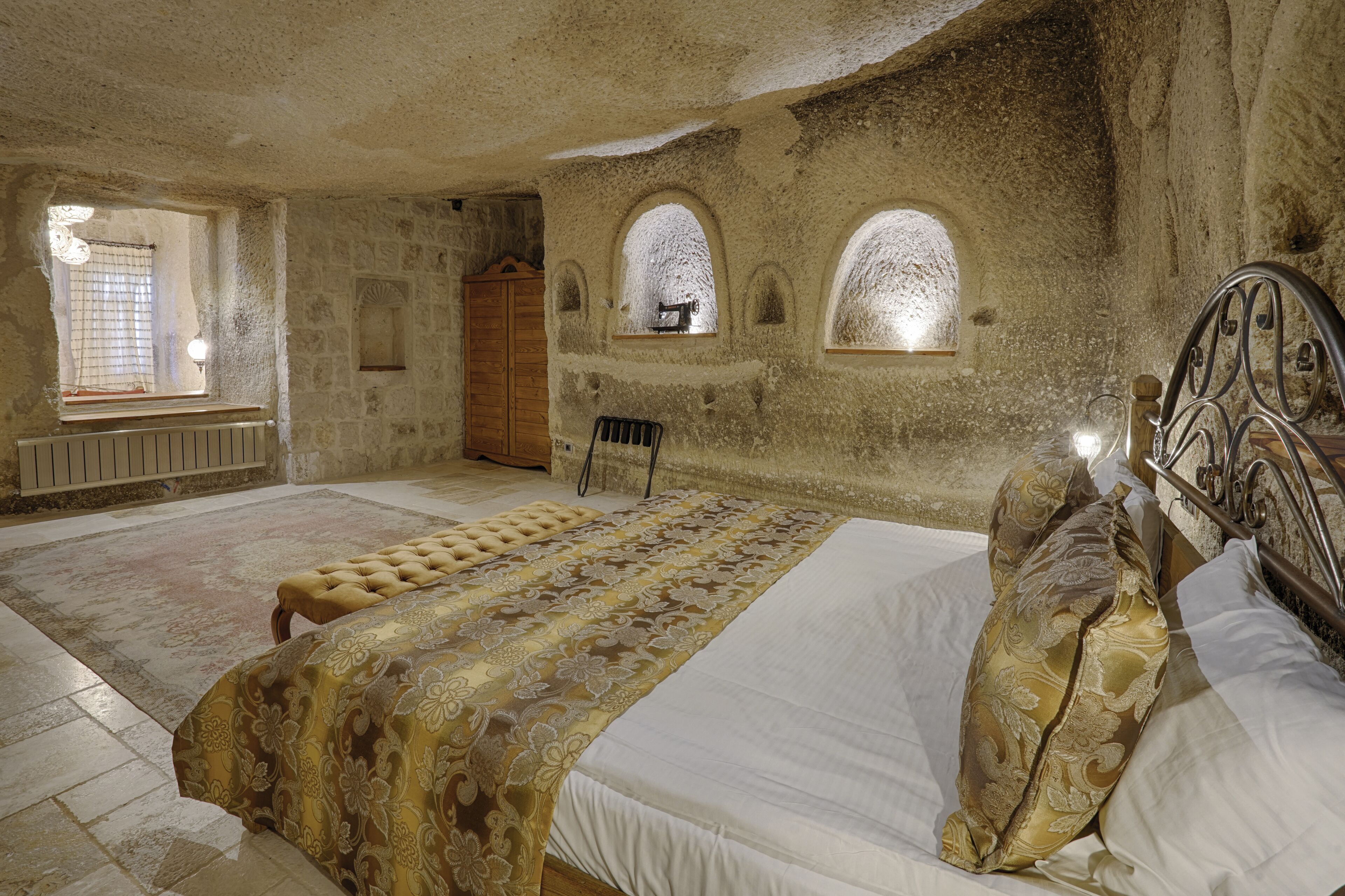 Une chambre à coucher avec un grand lit, une armoire en bois et des fenêtres en arc de cercle.