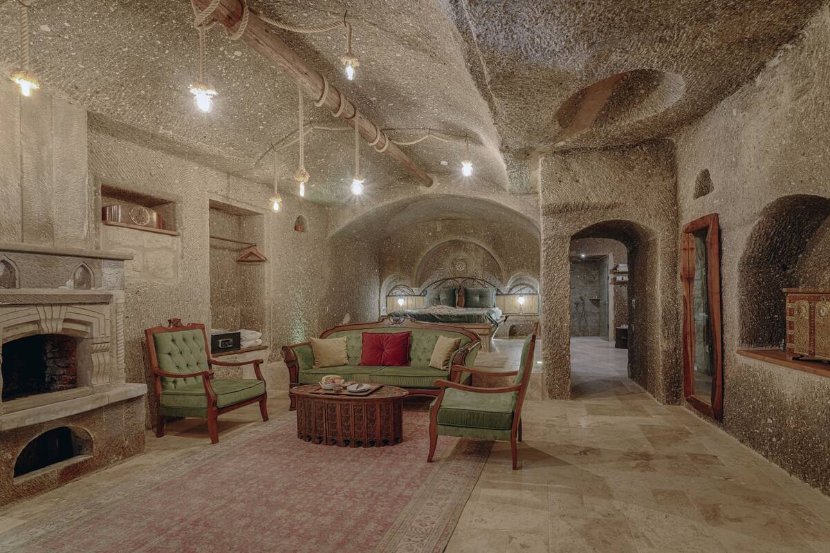 A spacious room with a fireplace, a green sofa, and a wooden coffee table.