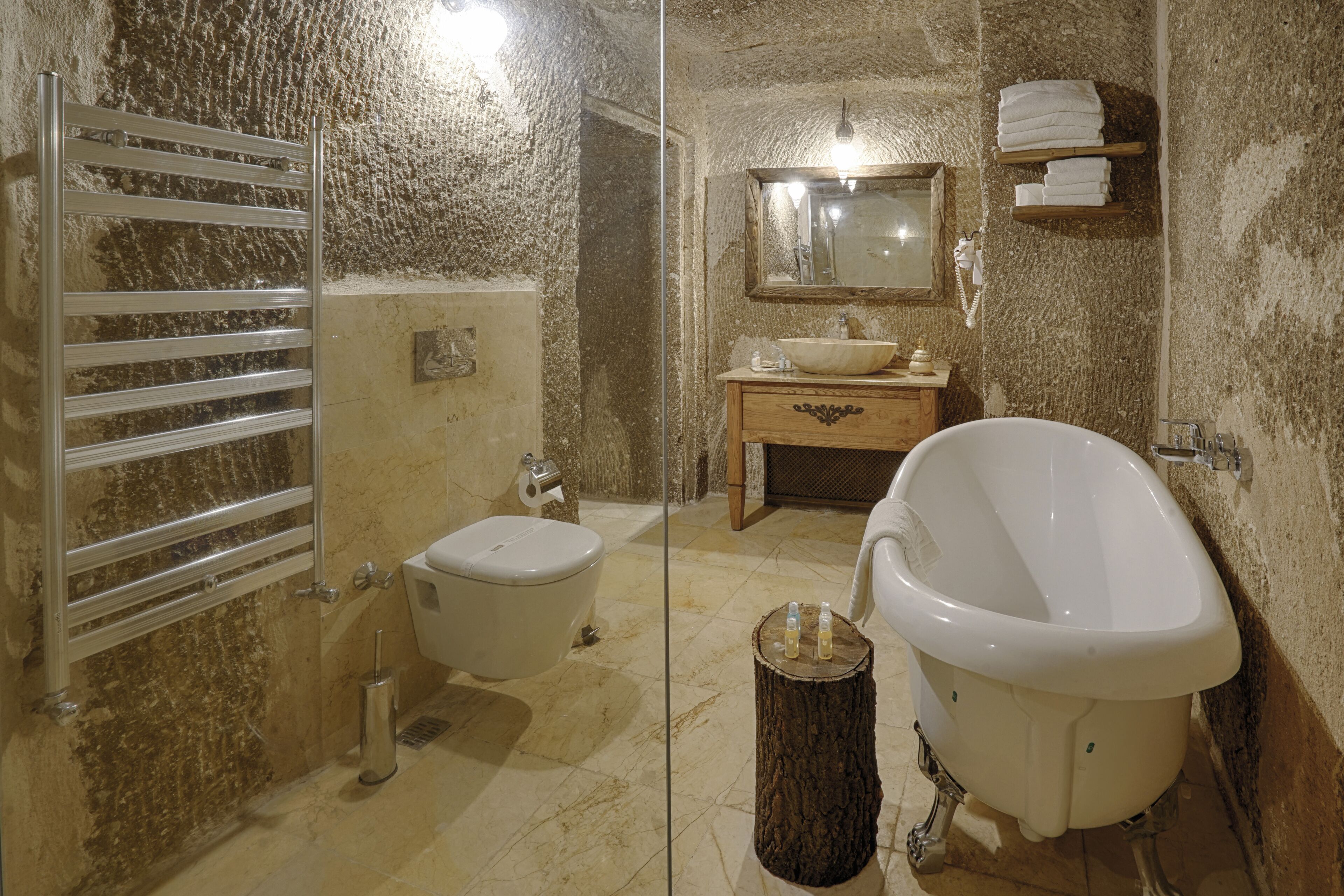 Un baño con bañera de patas de león, inodoro, lavabo y toallero.