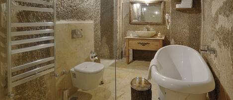 Un baño con bañera de patas de león, inodoro, lavabo y toallero.