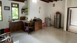 A spacious kitchen with wooden beams, a refrigerator, a sink, and a dining area with a table and chairs. - New Magnet Villa (Hikkaduwa)
