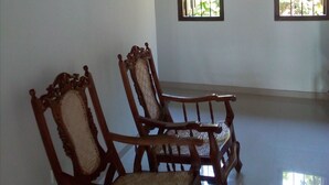 A room with two wooden chairs, a white wall, and two windows with bars. - New Magnet Villa (Hikkaduwa)