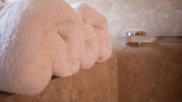 Una toalla blanca sobre una superficie de madera en un baño con pared de azulejos.
