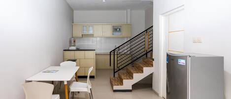 A modern kitchen with a dining area, a refrigerator, and a staircase.