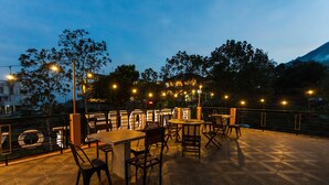 An outdoor seating area with tables and chairs, string lights, and a view of a mountain. - Batuque Town Villa 2 (Batu)