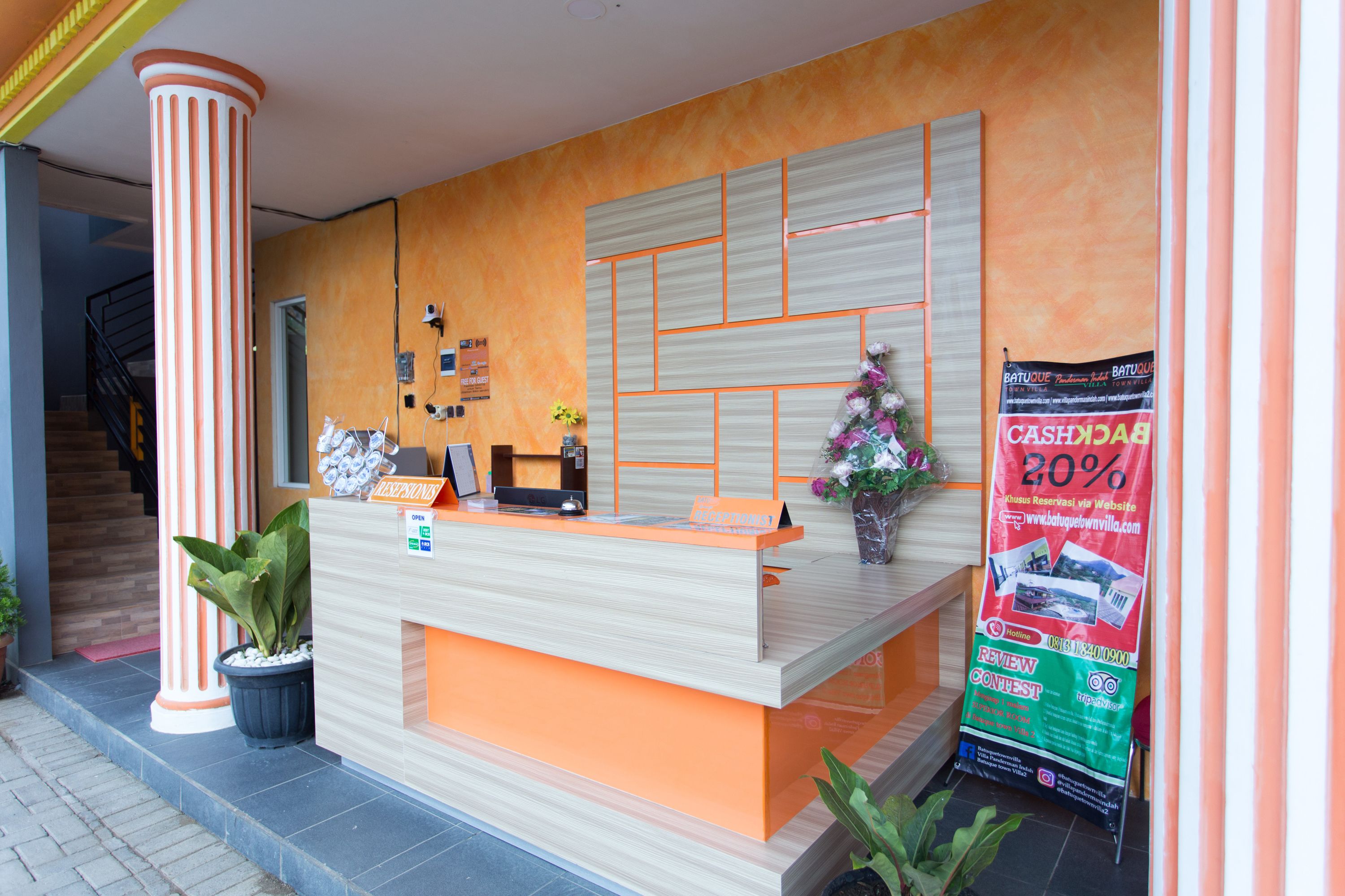 Un mostrador de recepción de diseño moderno, una escalera a la izquierda y un cartel promocional a la derecha.