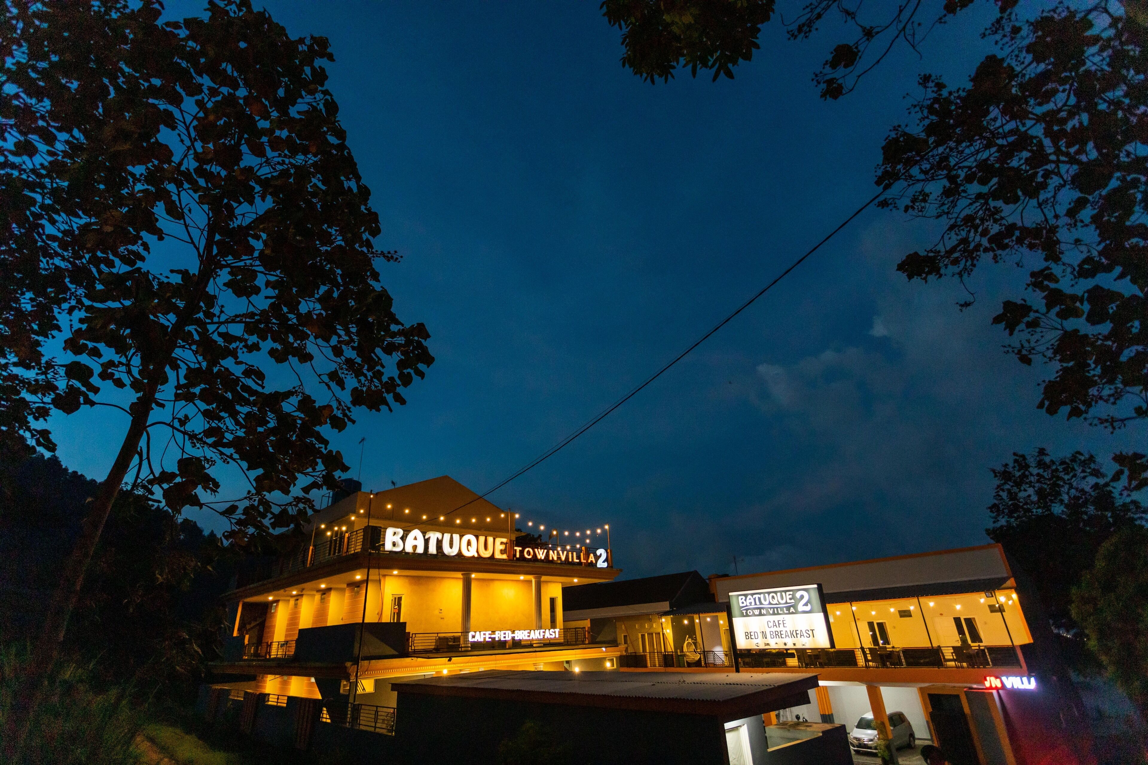 A multi-story building with a sign reading "Batuque Town Villa 2" and "Cafe-Food-Breakfast".
