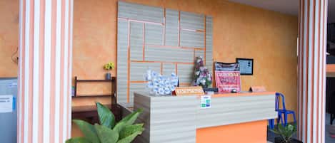 Un comptoir d’accueil au design moderne, une plante en pot et un panneau indiquant une réduction de 20 %.