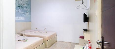 Habitación de hotel con dos camas, un escritorio pequeño con artículos de aseo, un mapa en la pared y una lámpara colgante.