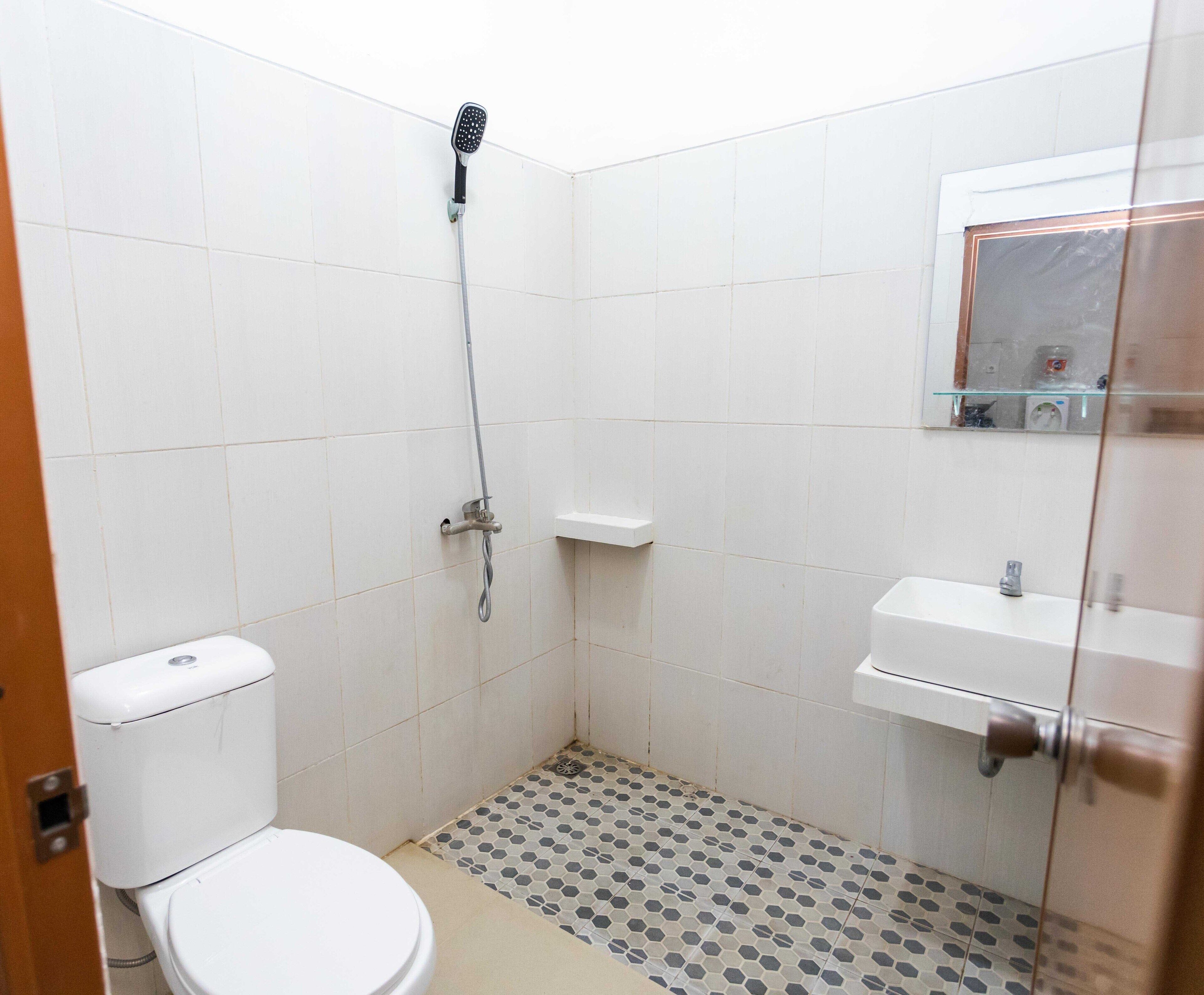 A small, tiled bathroom with a toilet, a shower, and a sink.