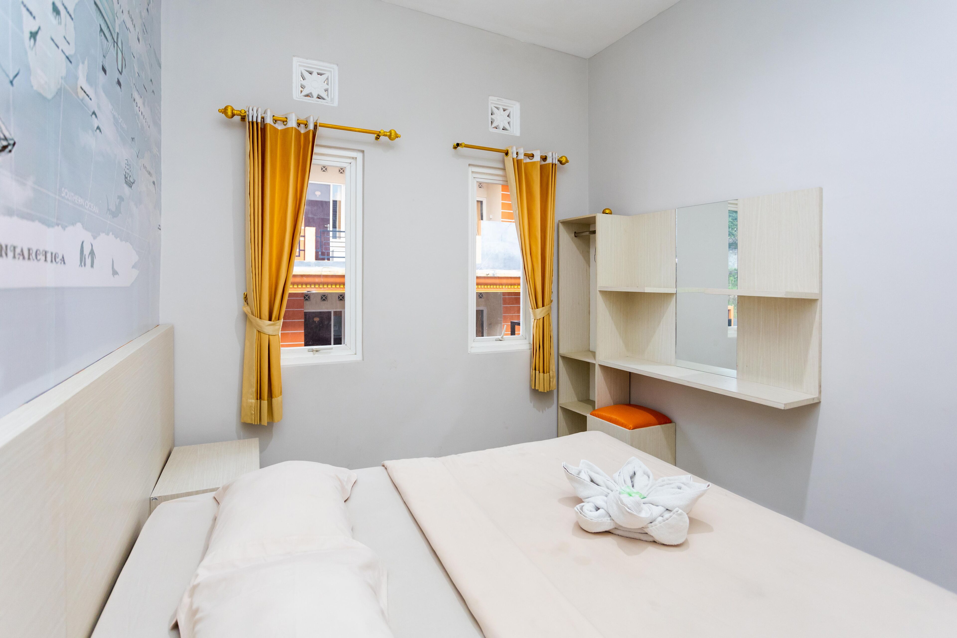 Una habitación de hotel con cama, ventana con cortinas, estante en la pared y una toalla sobre la cama.