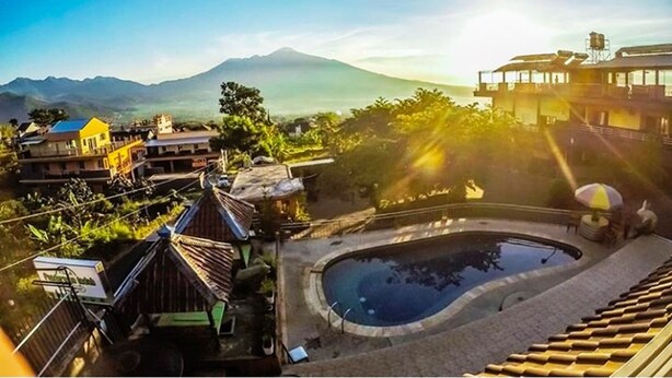 A residential area with a swimming pool, houses, and a mountain in the background. - Batuque Town Villa 2 (Batu)