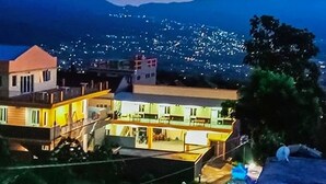 A residential area with a house featuring a balcony and a view of a cityscape with mountains in the background. - Batuque Town Villa 2 (Batu)