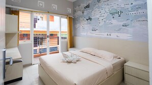 A hotel room with a bed, a nightstand, a wardrobe, and a window with a view of a balcony. - Batuque Town Villa 2 (Batu)