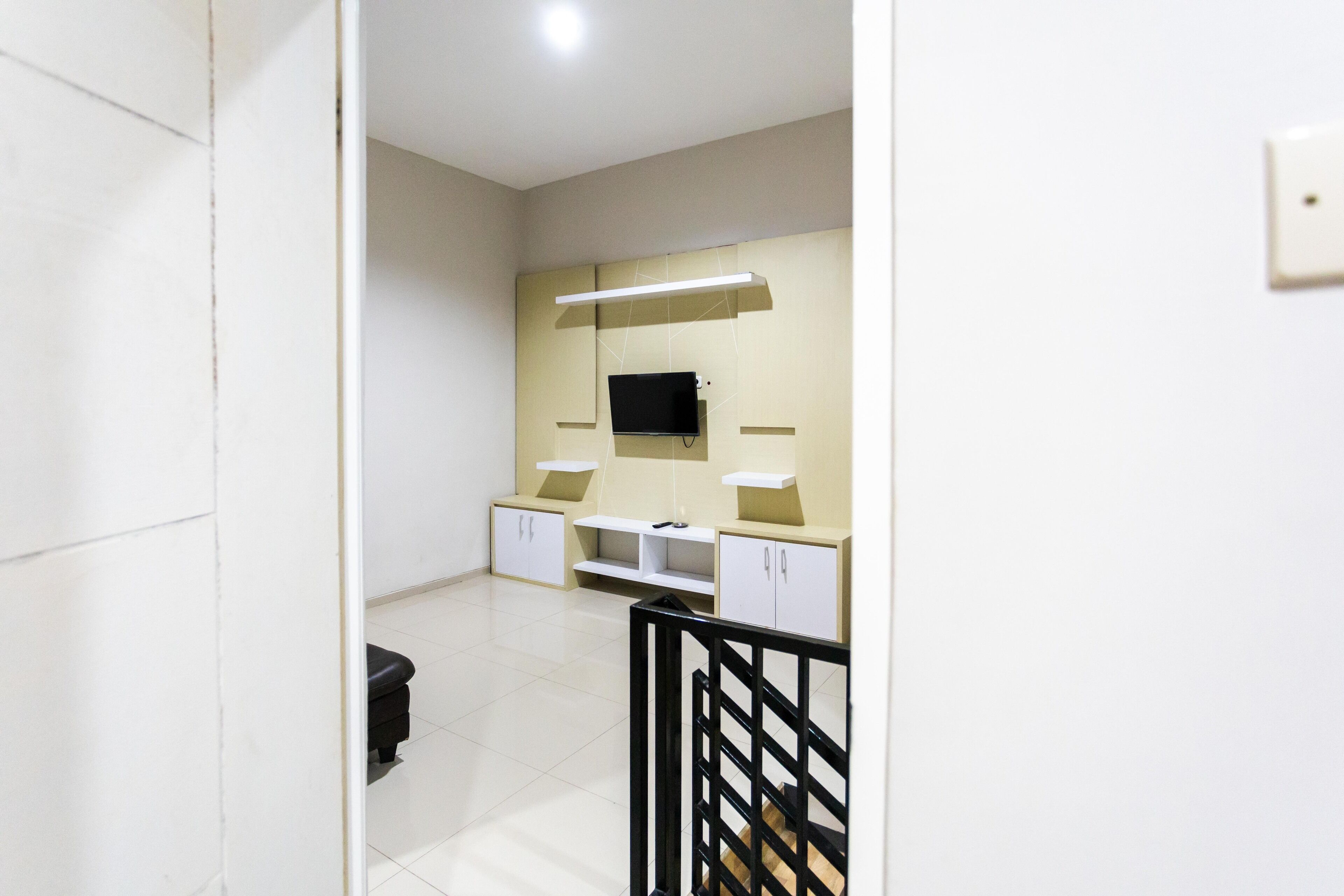 A hotel room with a flat-screen TV mounted on the wall, a small sofa, and a desk with a chair.
