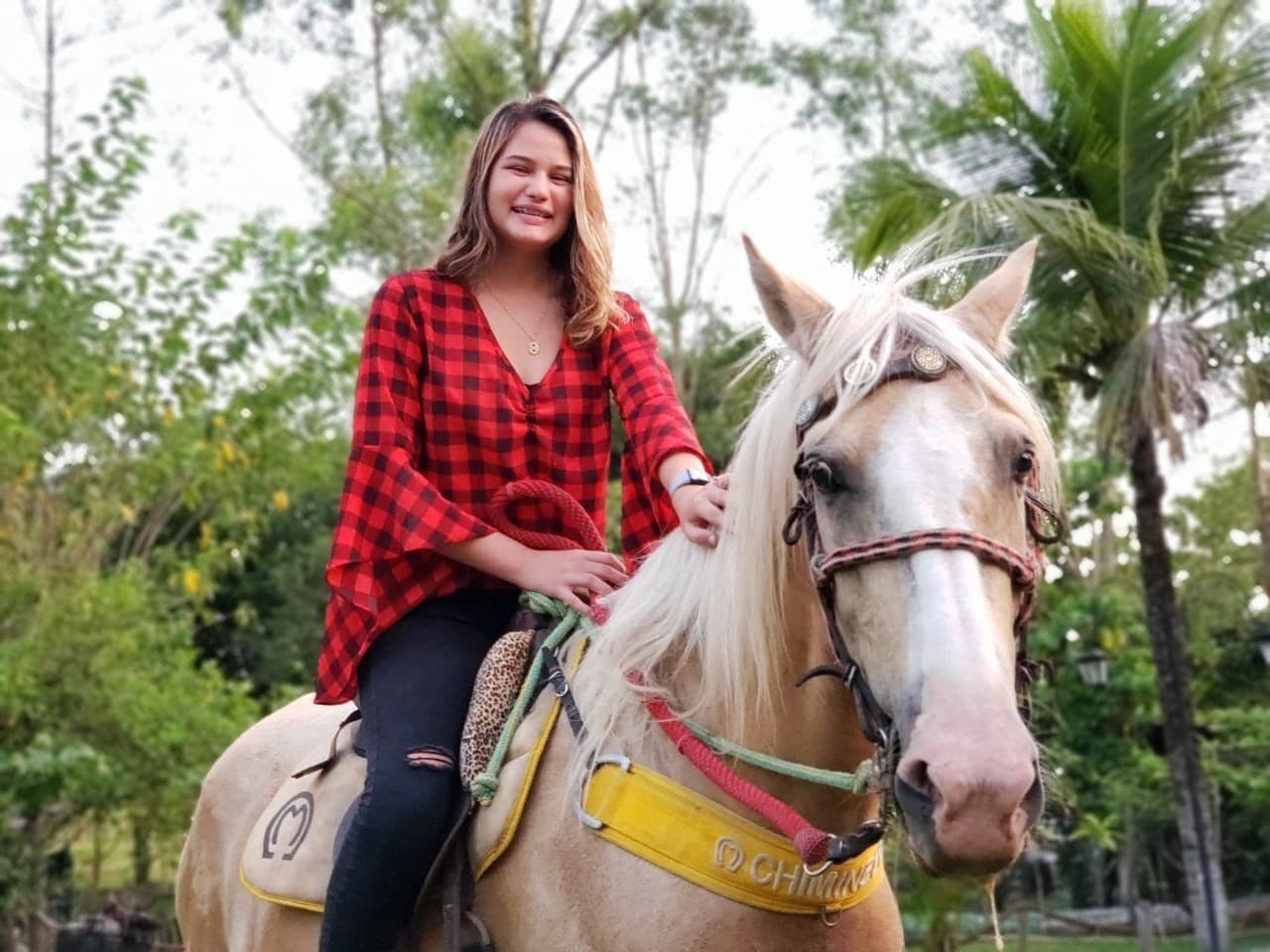 Una persona montando a caballo en un entorno natural, con árboles y vegetación de fondo.