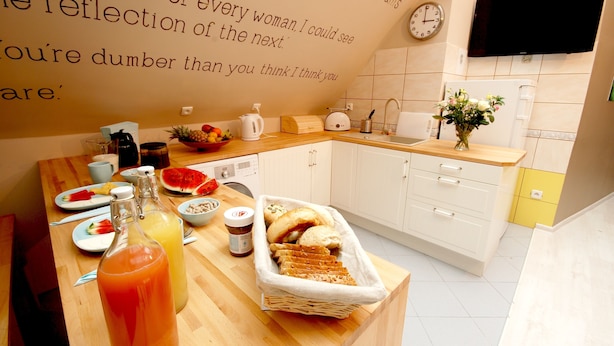 A modern kitchen with a wooden countertop, a sink, and a wall-mounted TV. - Rosemary's B&B (Poznan)