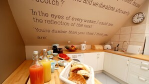 A kitchen with a wooden table, breakfast items, and a wall with motivational quotes. - Rosemary's B&B (Poznan)