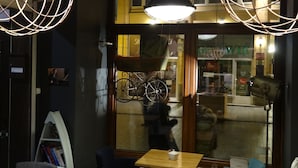 A cozy cafe interior with hanging lamps, a bicycle outside the window, and a visible shop sign. - Rosemary's B&B (Poznan)