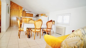A dining area with a table and chairs, a kitchen with wooden cabinets, and a radiator.