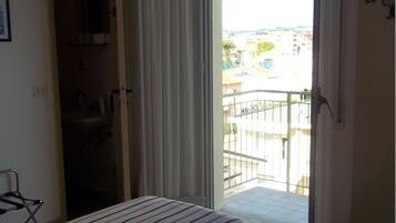 Una camera d'albergo con un letto, un bagno e un balcone con vista sulla città.