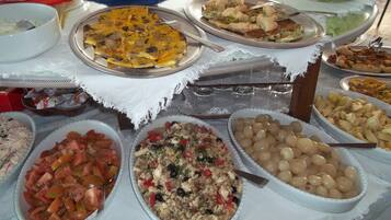 Ein reichhaltiges Buffet mit verschiedenen Speisen, darunter Salate, Reis und Pasta.