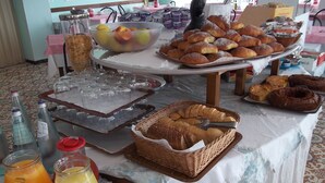 Un bufé de desayuno con diversos pasteles, pan y fruta.