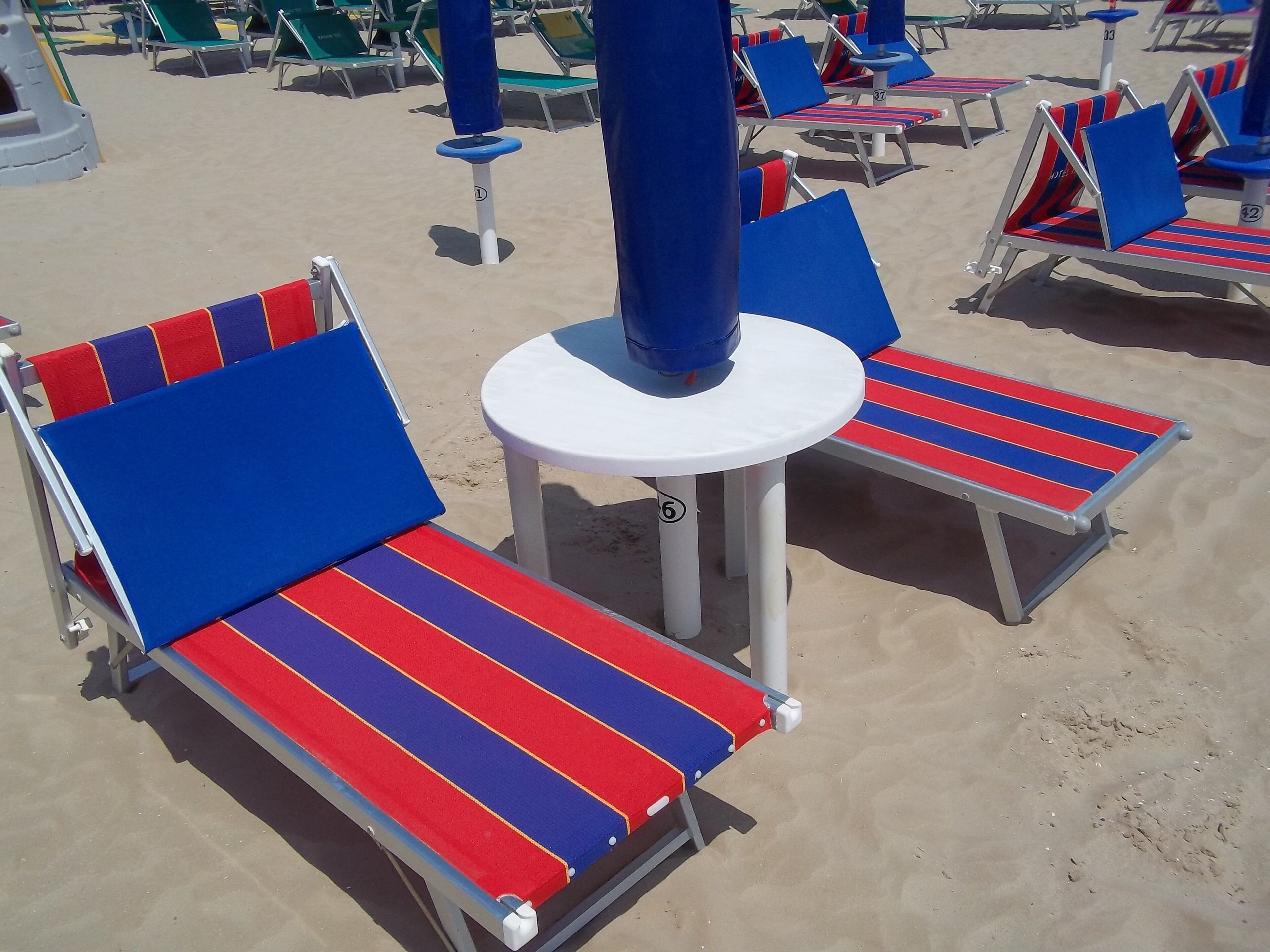 Une plage bordée de rangées de chaises longues et de parasols.