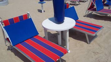 Une plage bordée de rangées de chaises longues et de parasols.