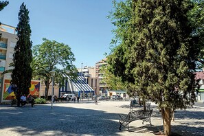 A public square with benches, trees, and buildings in the background. - Hostal Carrizo (Elda)