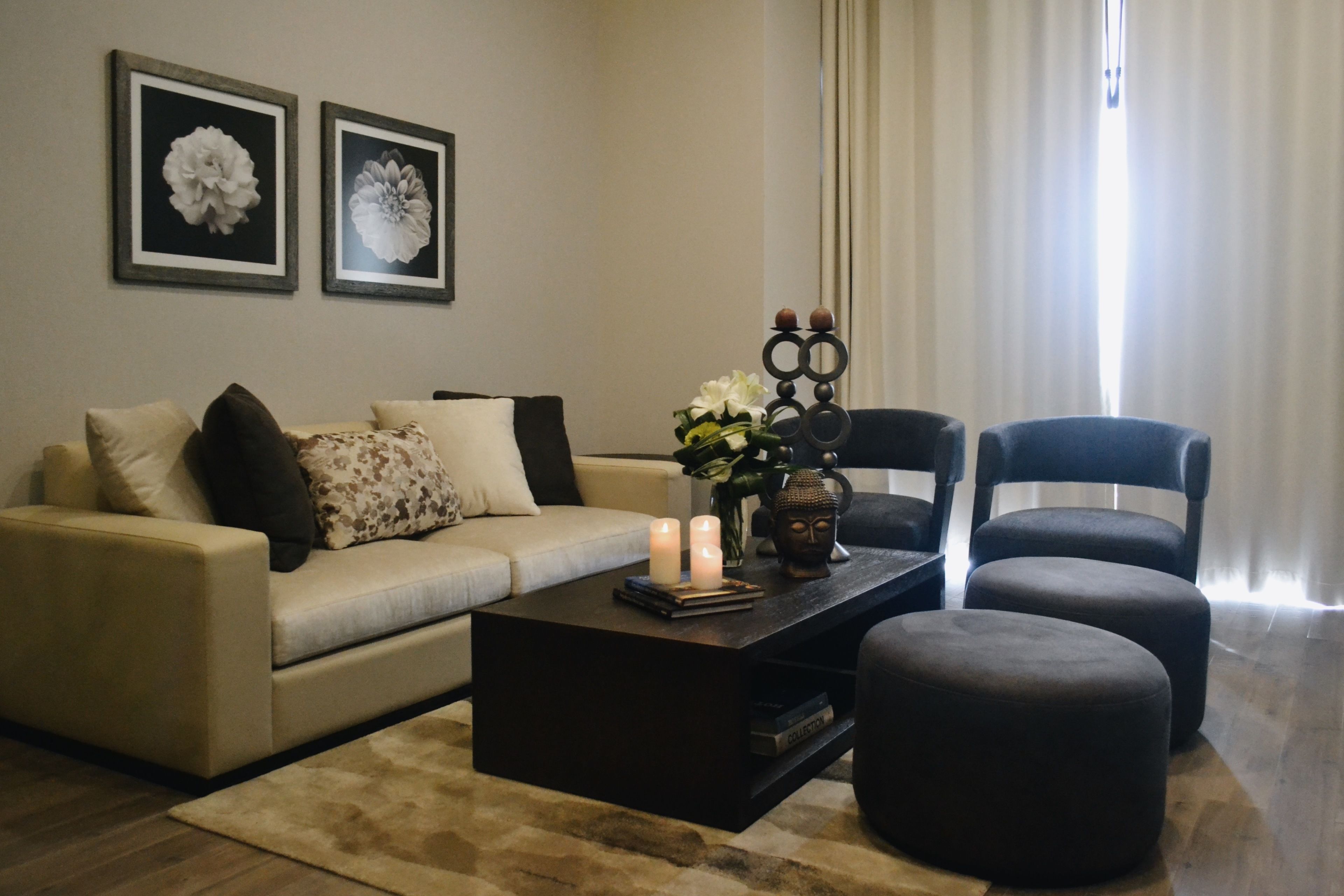 A living room with a sofa, two chairs, a coffee table, and a Buddha statue.