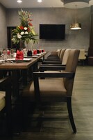 Comedor con una larga mesa dispuesta para varios invitados, sillas y un gran centro de mesa floral.