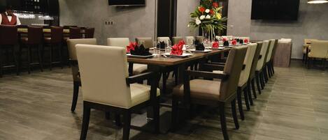 A modern dining area with a long table set for a meal, surrounded by chairs.