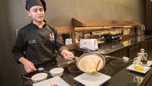 Un chef preparando comida en una cocina moderna con electrodomésticos de acero inoxidable y un diseño elegante.