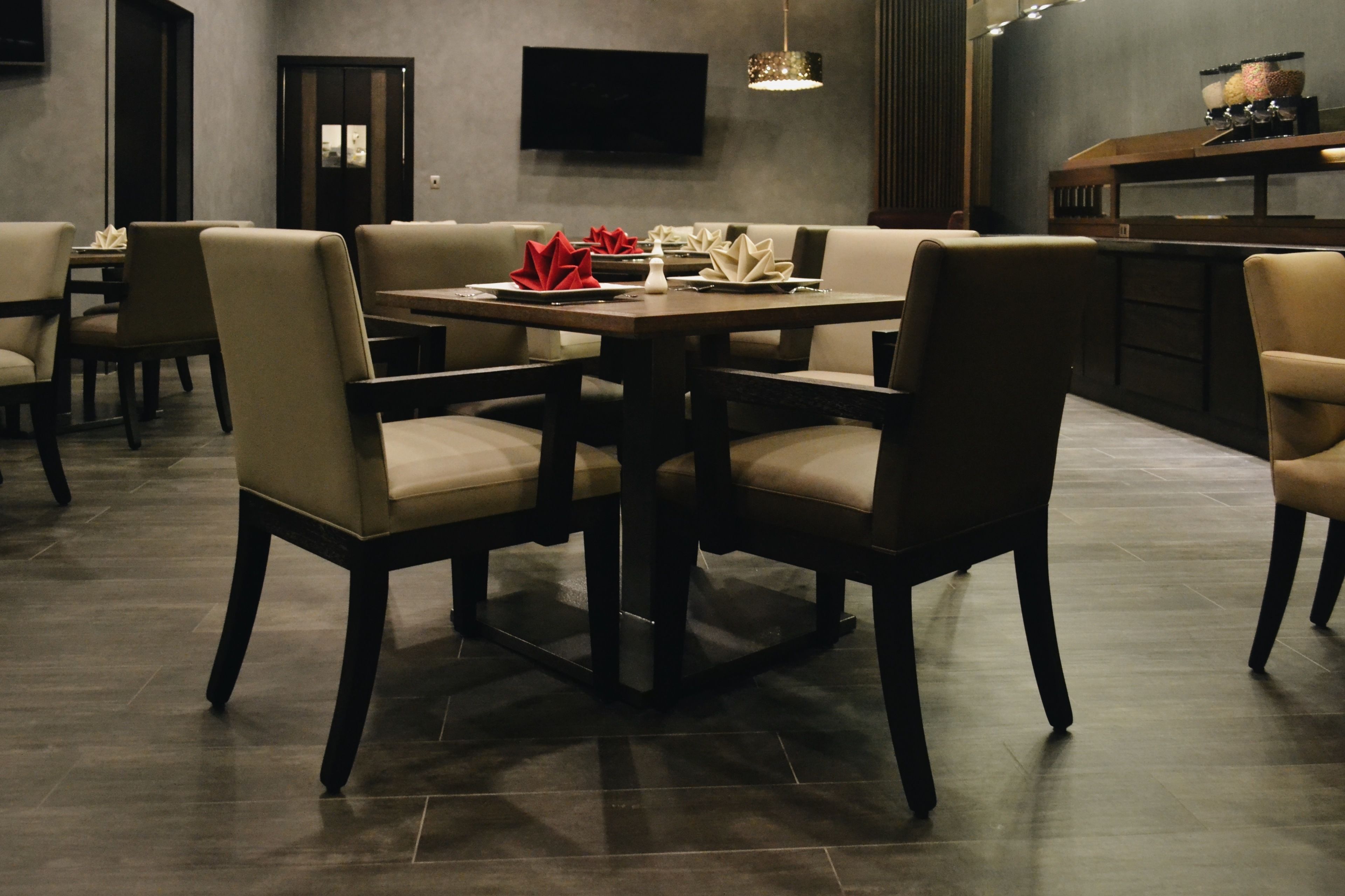Un espace repas moderne avec une table rectangulaire, des chaises rembourrées et un téléviseur à écran plat fixé au mur.