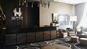 Una moderna zona de recepción de hotel con un mostrador oscuro, un cuadro abstracto de gran tamaño y asientos cómodos.