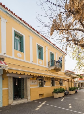 A yellow building with a balcony and a sign that reads "Milos."