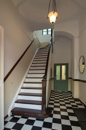 A staircase with a checkered floor leading to a green door.