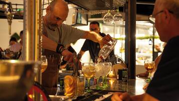 Een barman schenkt een drankje in een glas in aan de bar.
