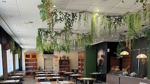 Un restaurante con varias mesas, plantas colgantes y una zona de bar.