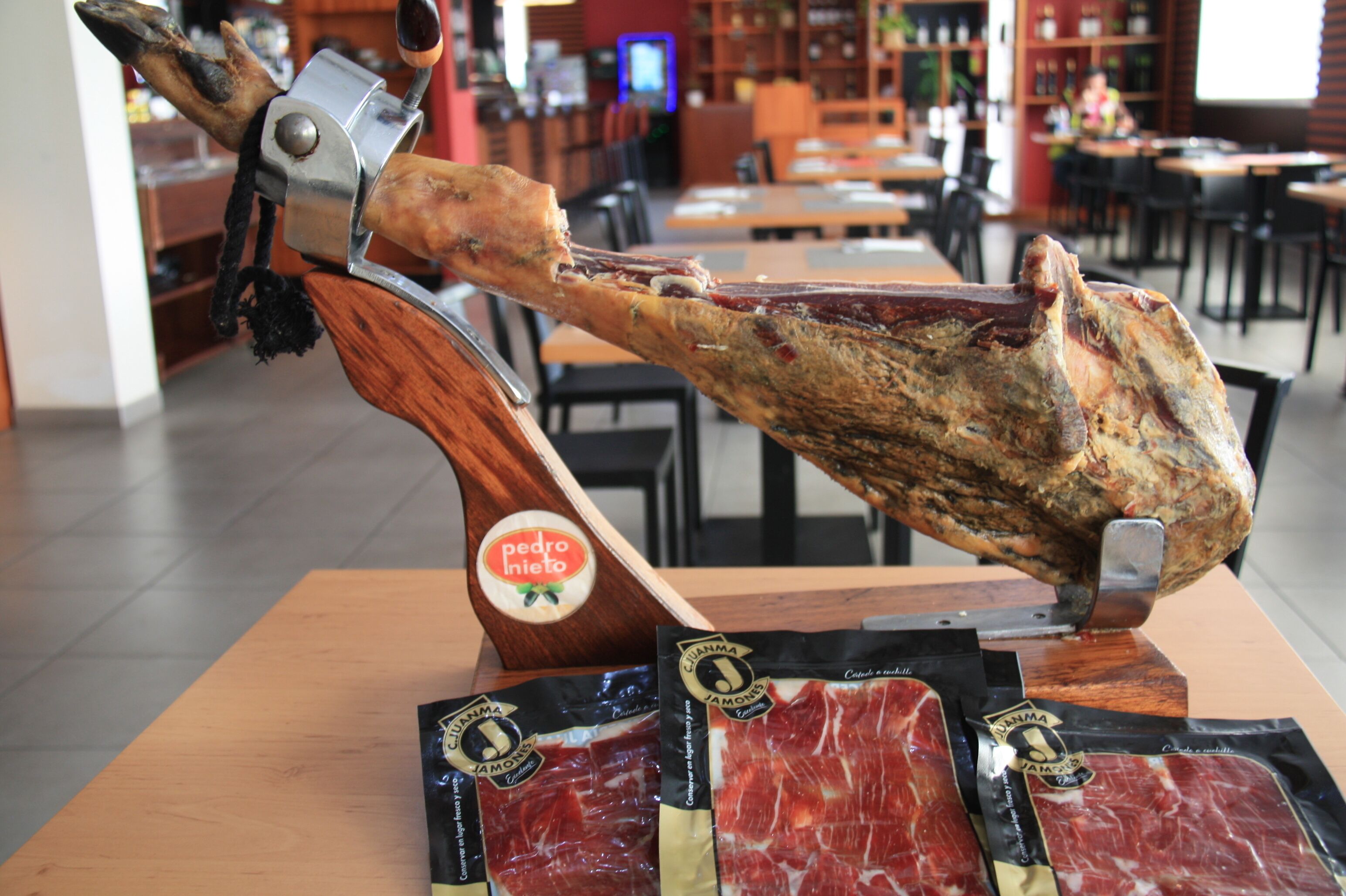 Una estación de preparación de carnes frías con un jamón entero asado y varios paquetes de embutidos.