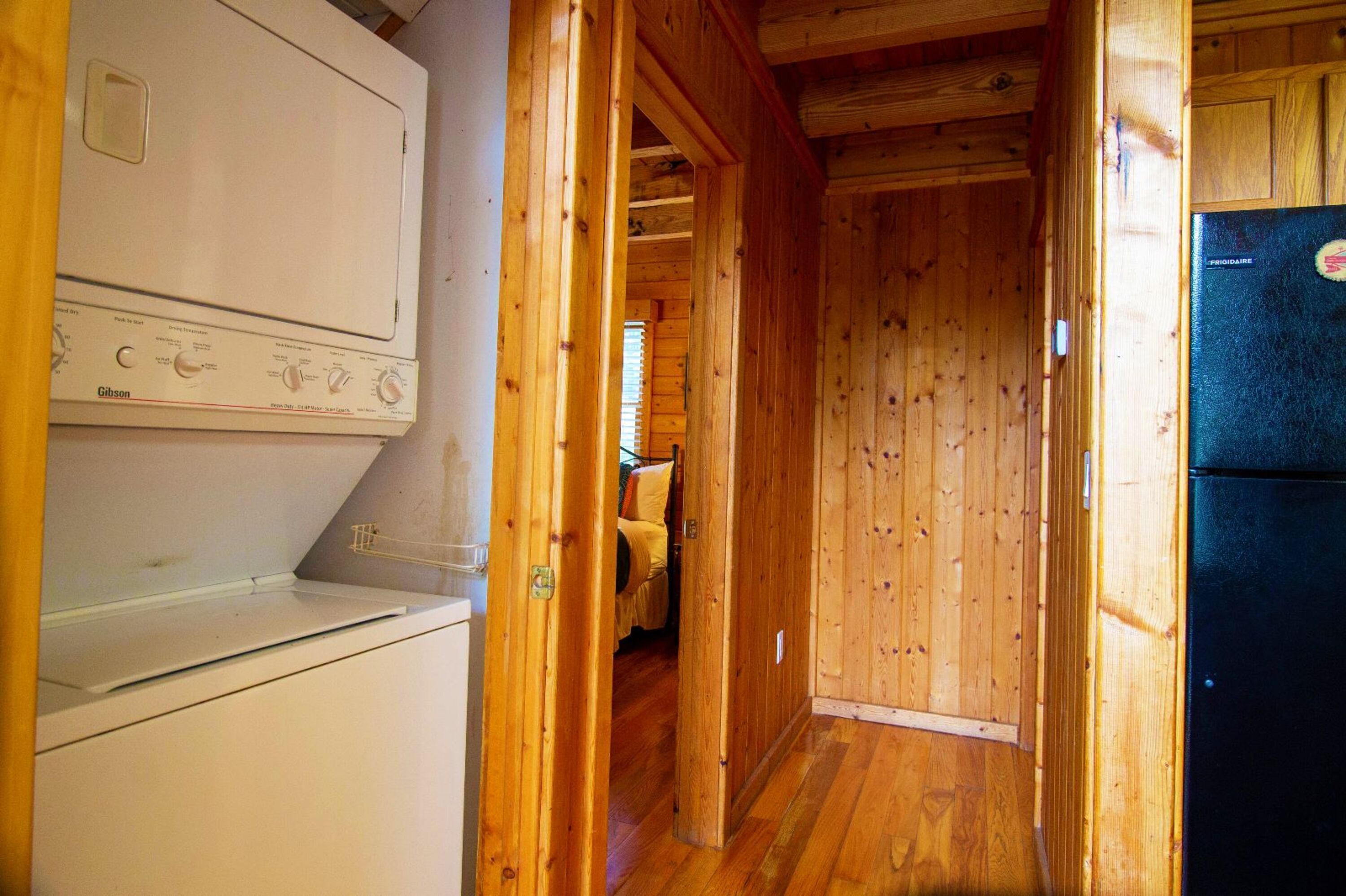 Un interior de madera con un electrodoméstico blanco y un refrigerador negro.