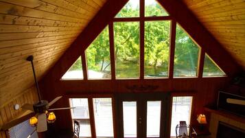 A wooden interior with a large window, a ceiling fan, and a fireplace.